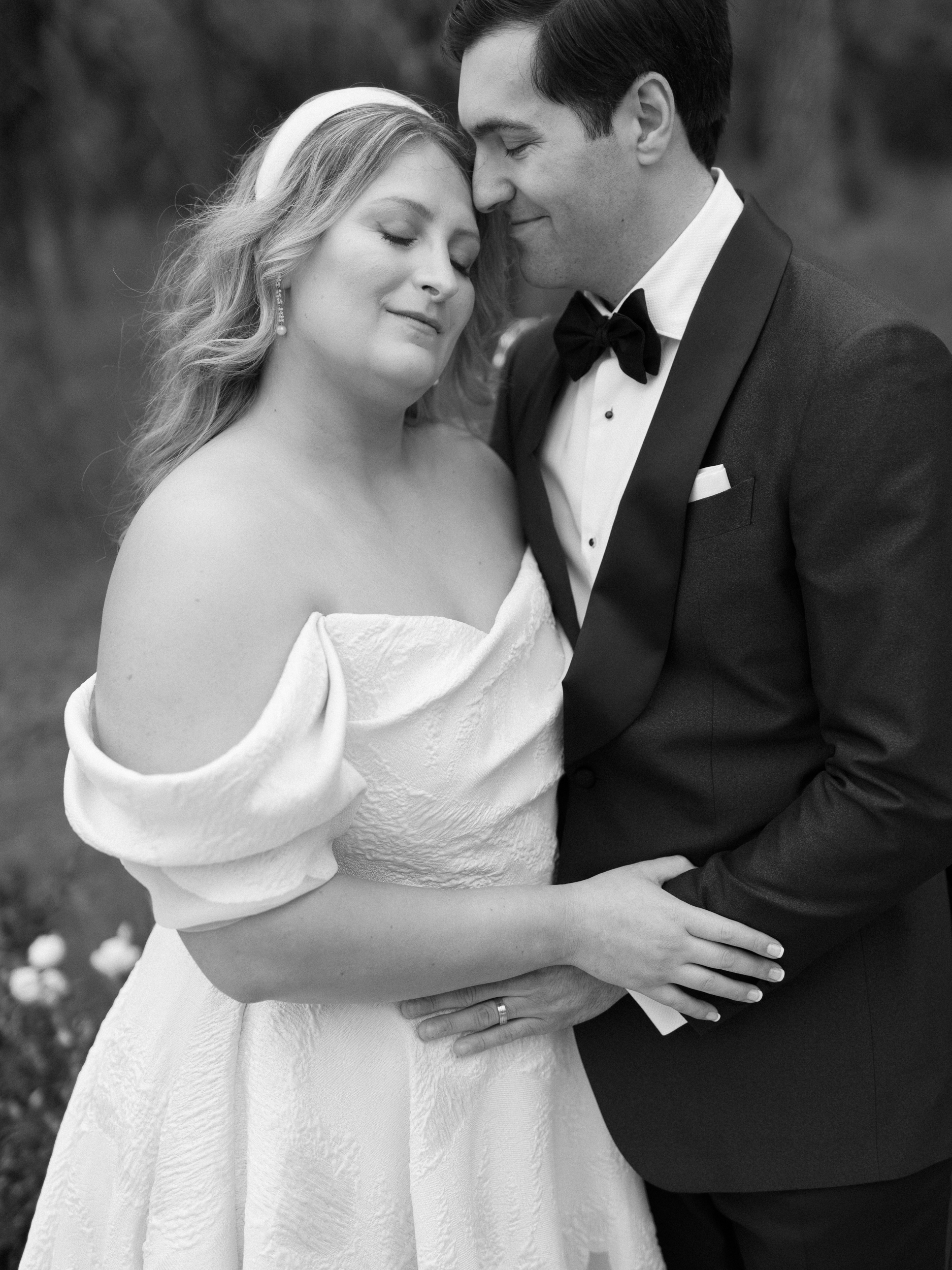 A black and white portrait of a bride and groom hugging each other at the Grand Lady wedding ceremony lawn