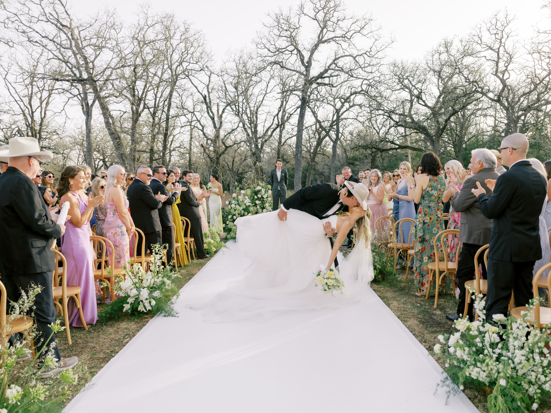 Bride and groom dip and kiss on their walk back up the aisle after their Grand Lady wedding ceremony in front of the mansion